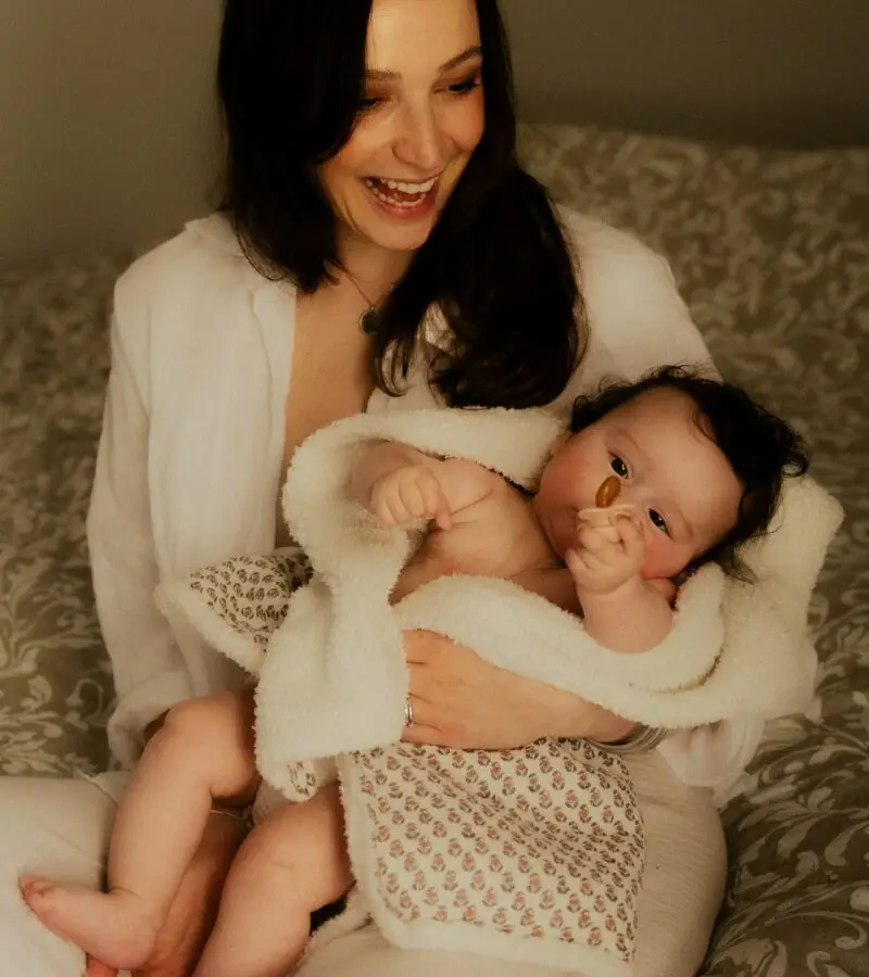 Maman souriante tenant son nouveau-né en peau à peau lors d'une séance naissance en studio - Melissa Jai Photographe