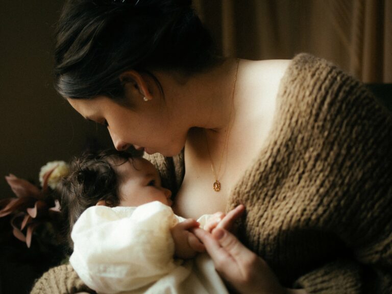 Gros plan allaitement maman allaitant bebe avec collier dore lumiere chaude photographe Melissa Jai