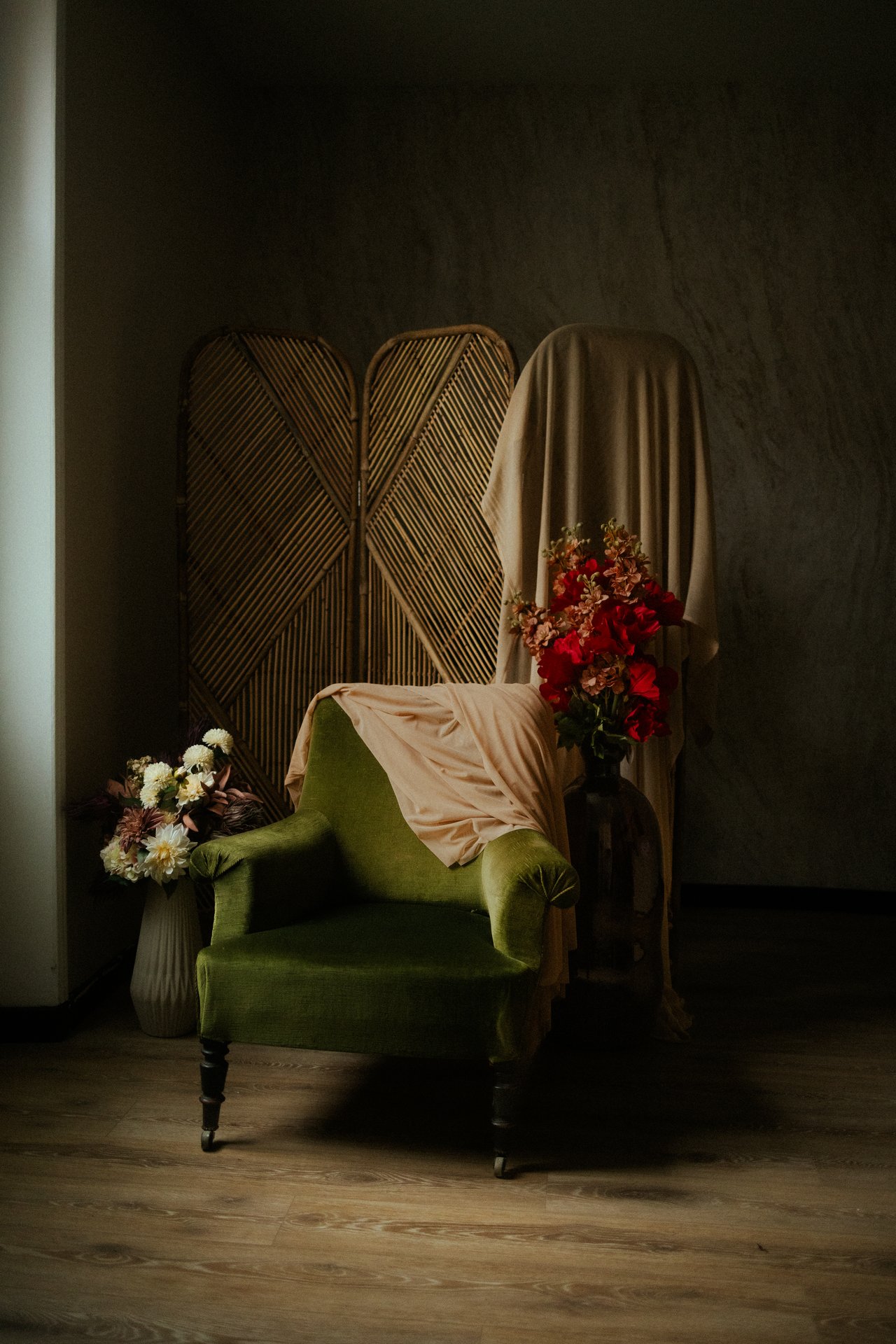 Decor de studio photo avec fauteuil en velours vert, bouquets de fleurs et paravent en rotin - Melissa Jai Photographe