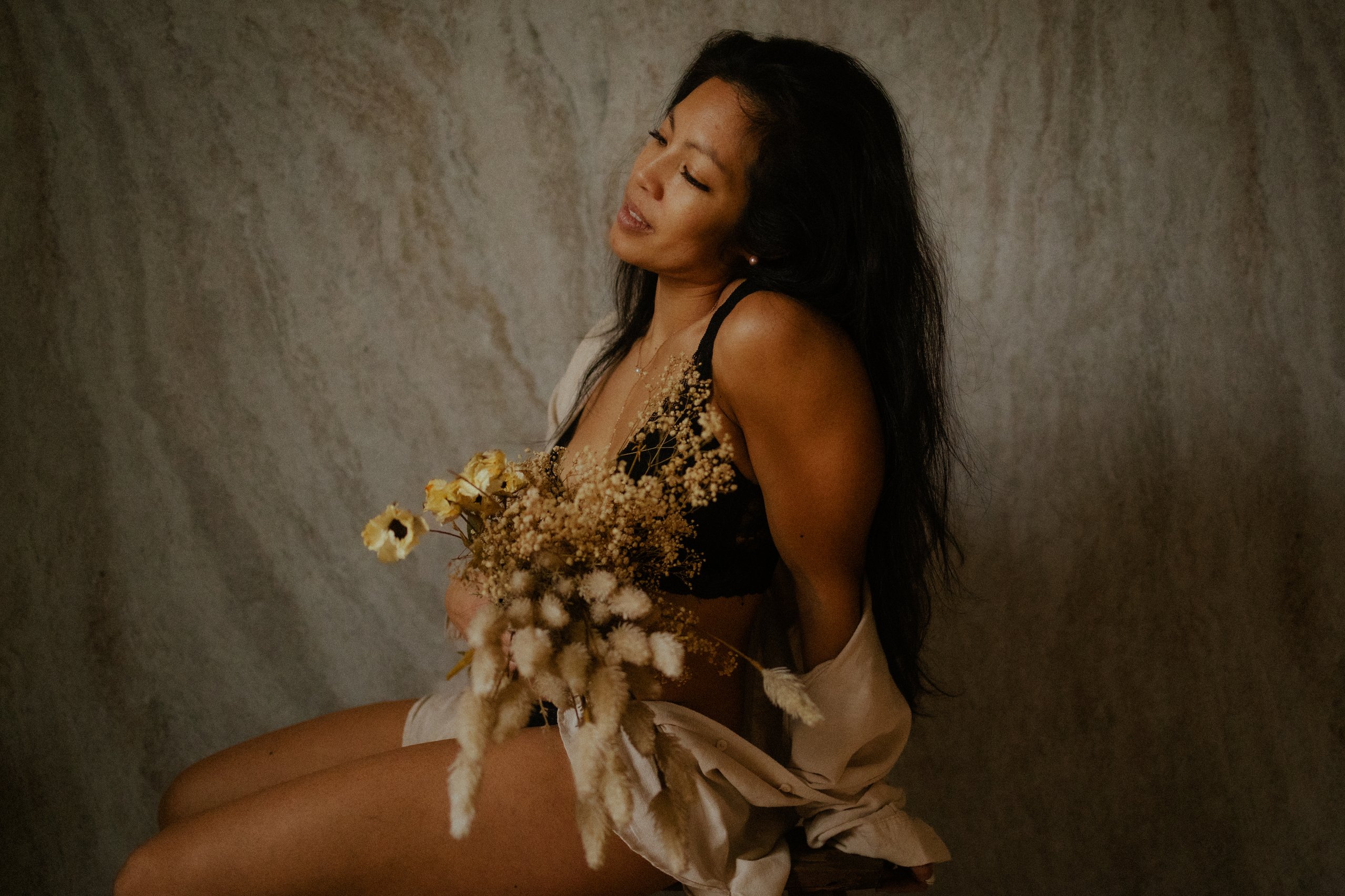 Portrait d une femme souriante les yeux fermes tenant un bouquet de fleurs sechees en lumiere douce naturelle - Melissa Jai Photographe