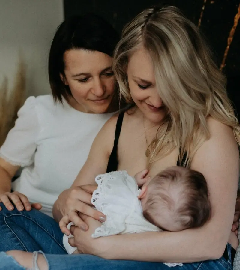Deux mamans souriantes tenant leur bébé lors d'une séance photo famille homoparentale - Melissa Jai Photographe