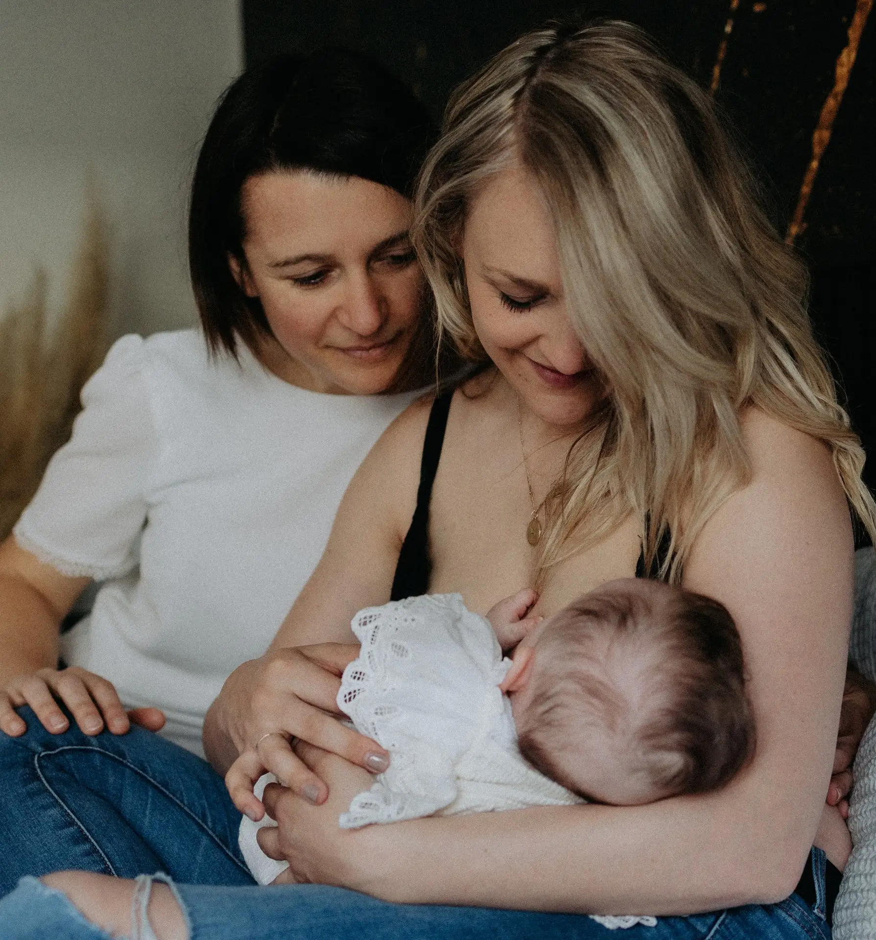 Deux mamans souriantes tenant leur bébé lors d'une séance photo famille homoparentale - Melissa Jai Photographe