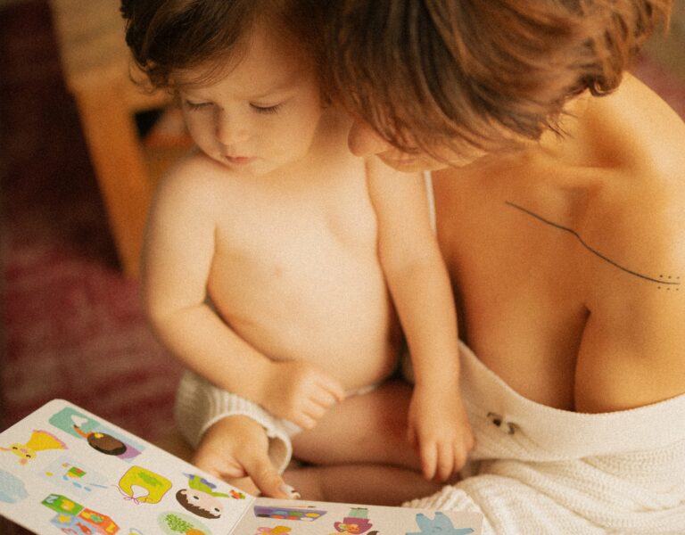 Maman et bébé en couche lisant ensemble un livre d'images coloré lors d'une séance photo famille lifestyle intime et chaleureuse