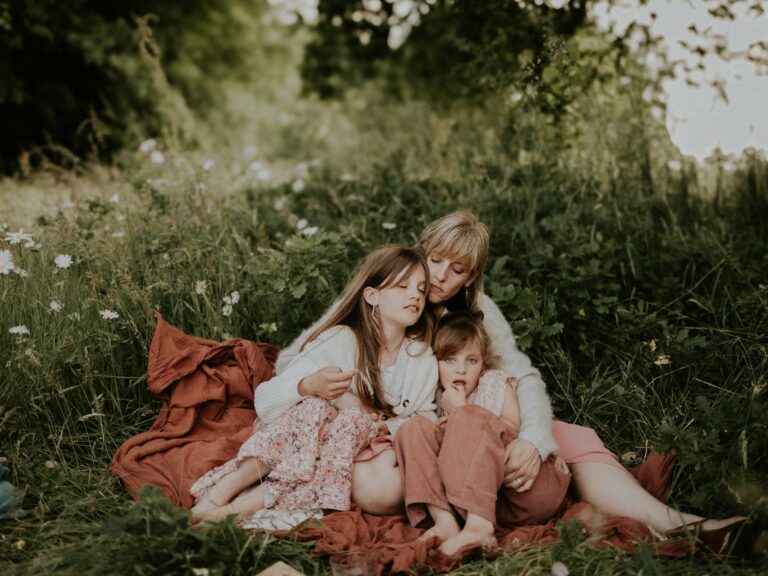Seance photo famille maman avec deux filles assises dans l herbe en exterieur photographe Melissa Jai
