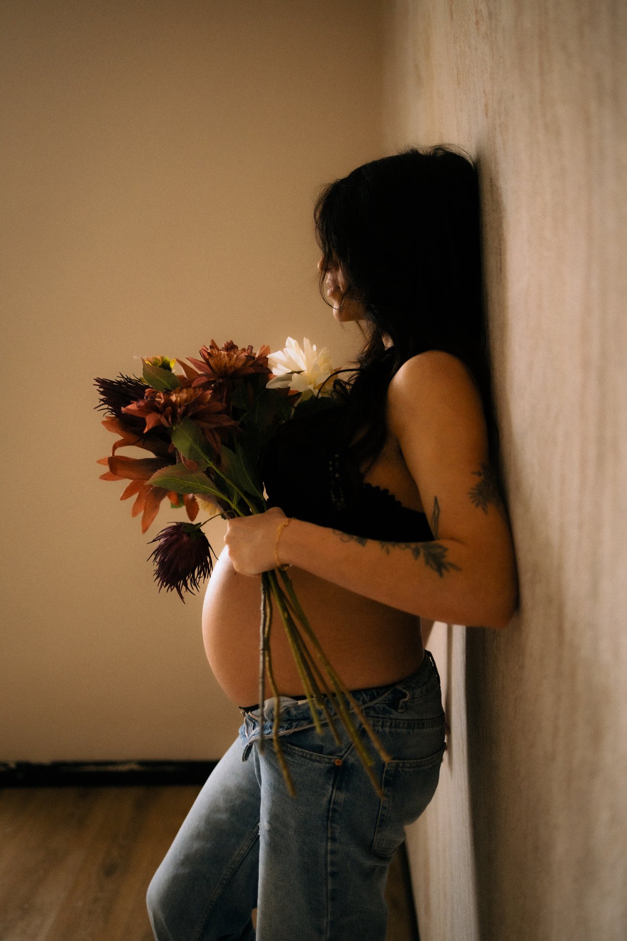 Femme enceinte tenant un bouquet de fleurs en lumiere doree lors d'une seance grossesse - Melissa Jai Photographe