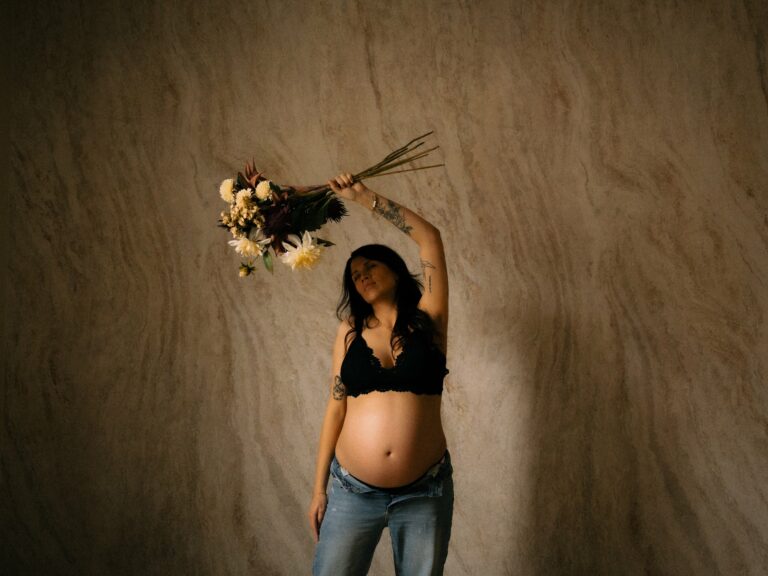 Seance photo grossesse femme enceinte tenant un bouquet de fleurs en studio portrait artistique photographe Melissa Jai