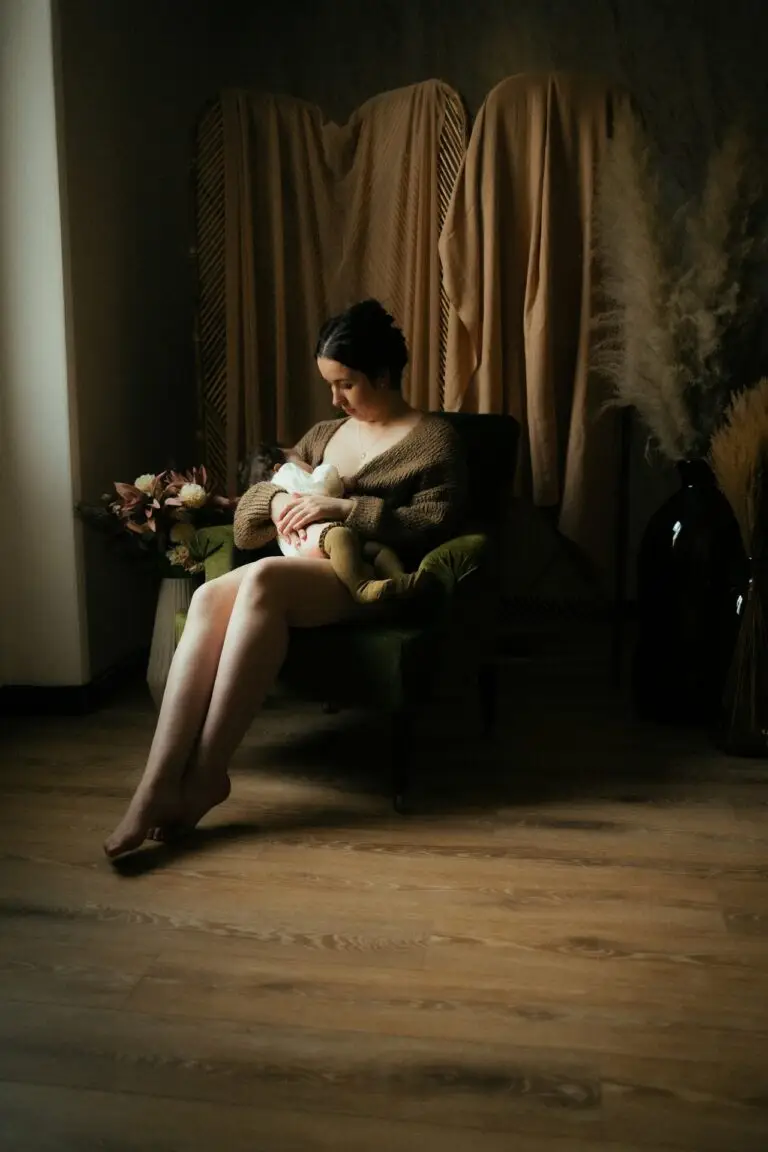 Femme enceinte assise sur un fauteuil en robe blanche lors d'une séance grossesse en studio - Melissa Jai Photographe