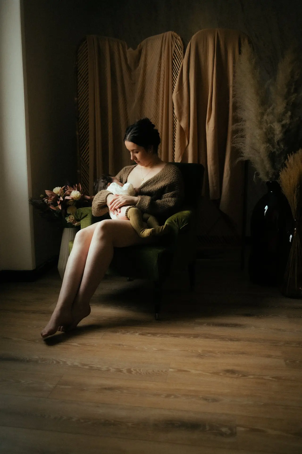 Femme enceinte assise sur un fauteuil en robe blanche lors d'une séance grossesse en studio - Melissa Jai Photographe
