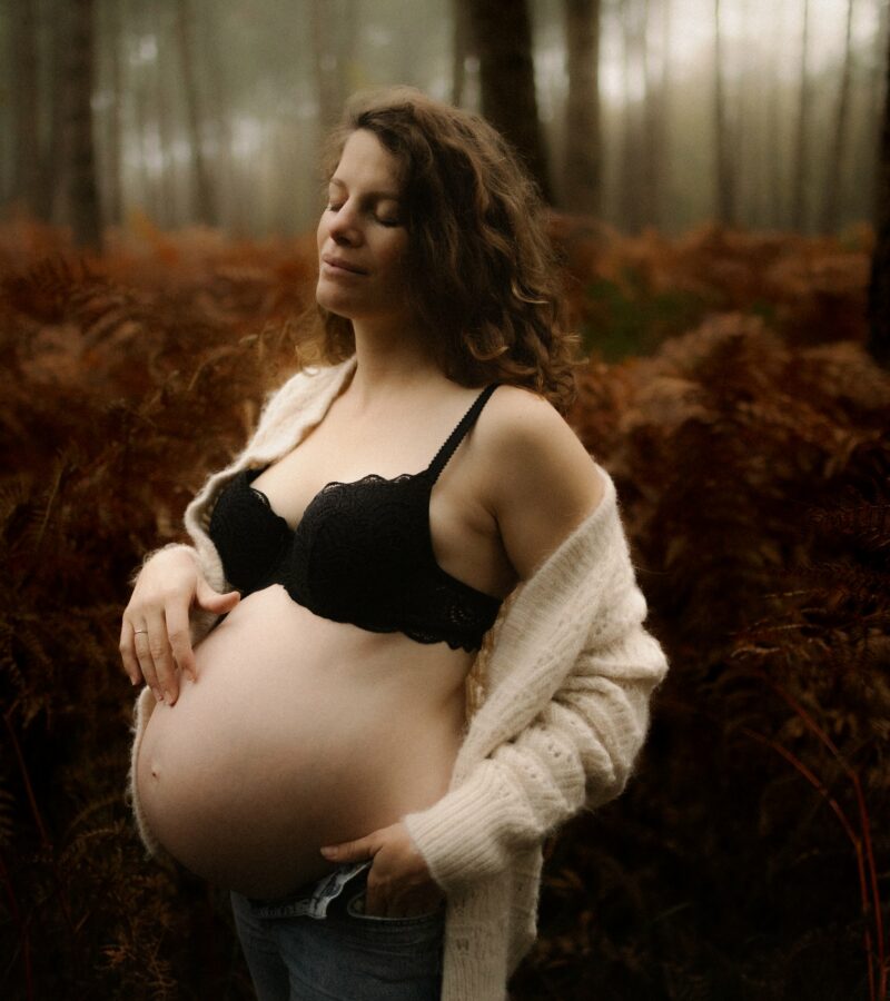Femme enceinte posant en exterieur dans un decor automnal lors d'une seance grossesse - Melissa Jai Photographe