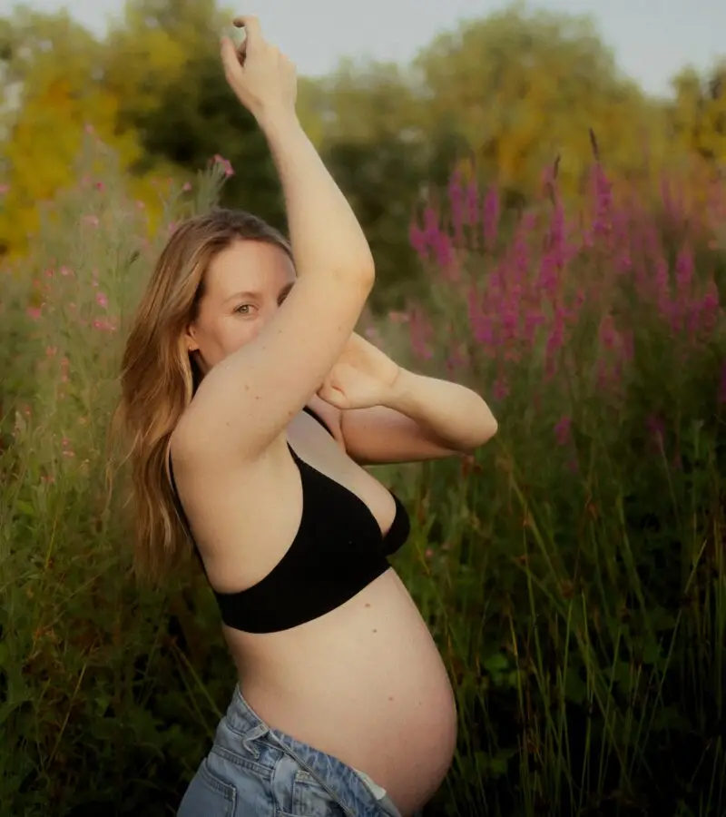Femme enceinte posant dans la nature verdoyante lors d'une séance grossesse en extérieur - Melissa Jai Photographe
