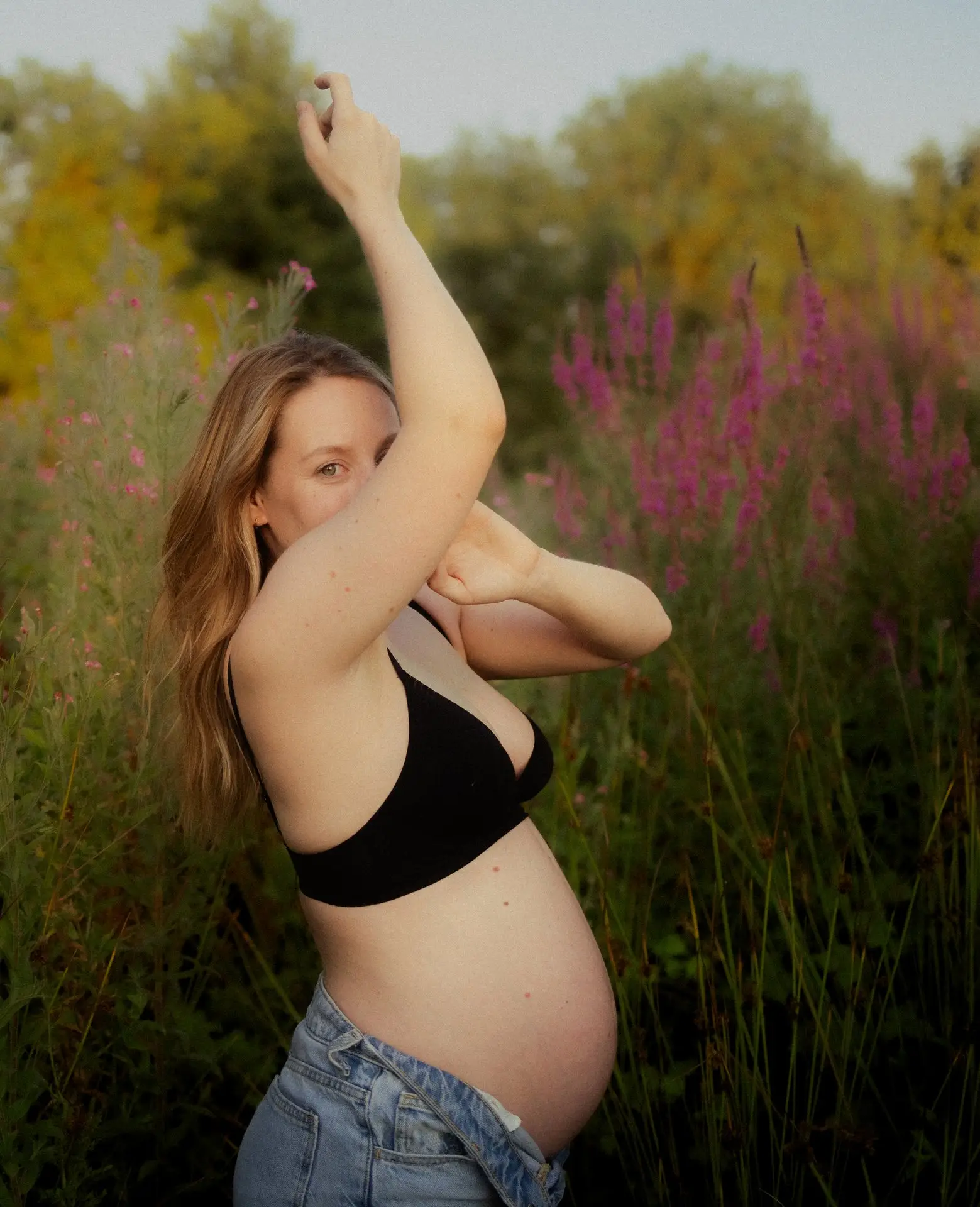 Femme enceinte posant dans la nature verdoyante lors d'une séance grossesse en extérieur - Melissa Jai Photographe