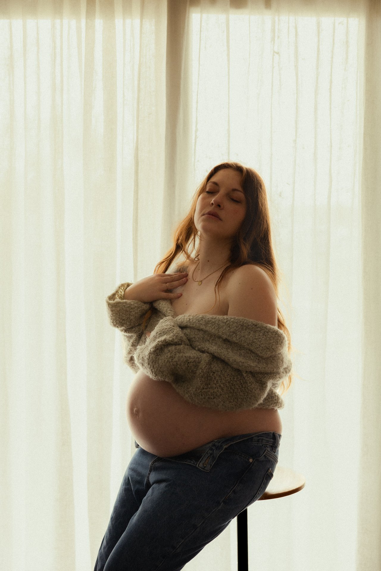 Portrait intimiste d'une femme enceinte les yeux fermés en lumière douce lors d'une séance grossesse - Melissa Jai Photographe
