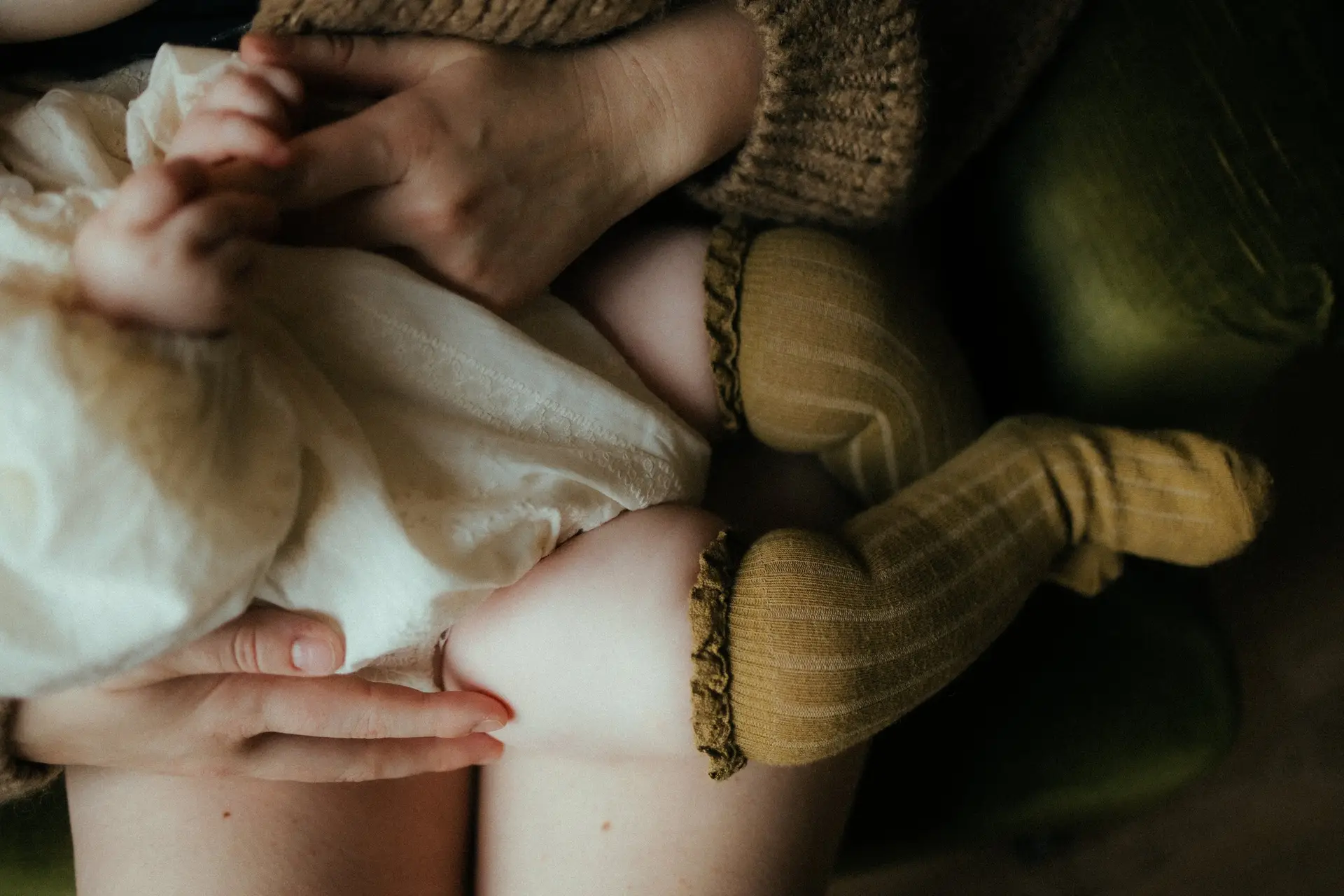 Détail des petits pieds d'un nouveau-né posés sur des coussins douillets lors d'une séance naissance à domicile - Melissa Jai Photographe