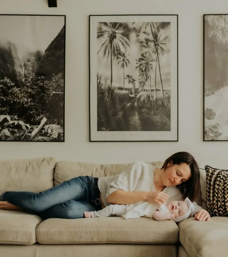 Maman allongée sur le canapé avec son bébé lors d'une séance naissance lifestyle à domicile - Melissa Jai Photographe