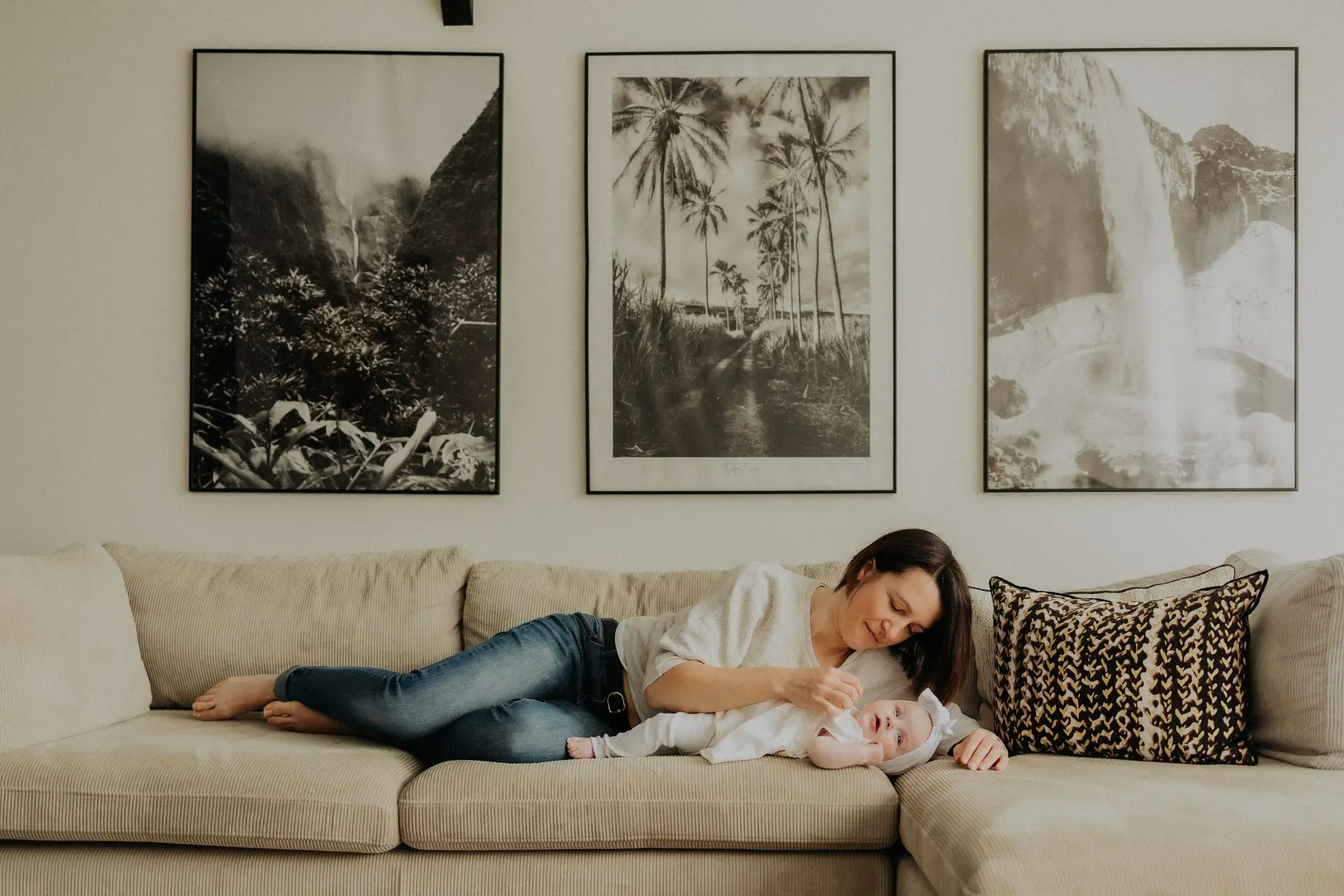 Maman allongée sur le canapé avec son bébé lors d'une séance naissance lifestyle à domicile - Melissa Jai Photographe