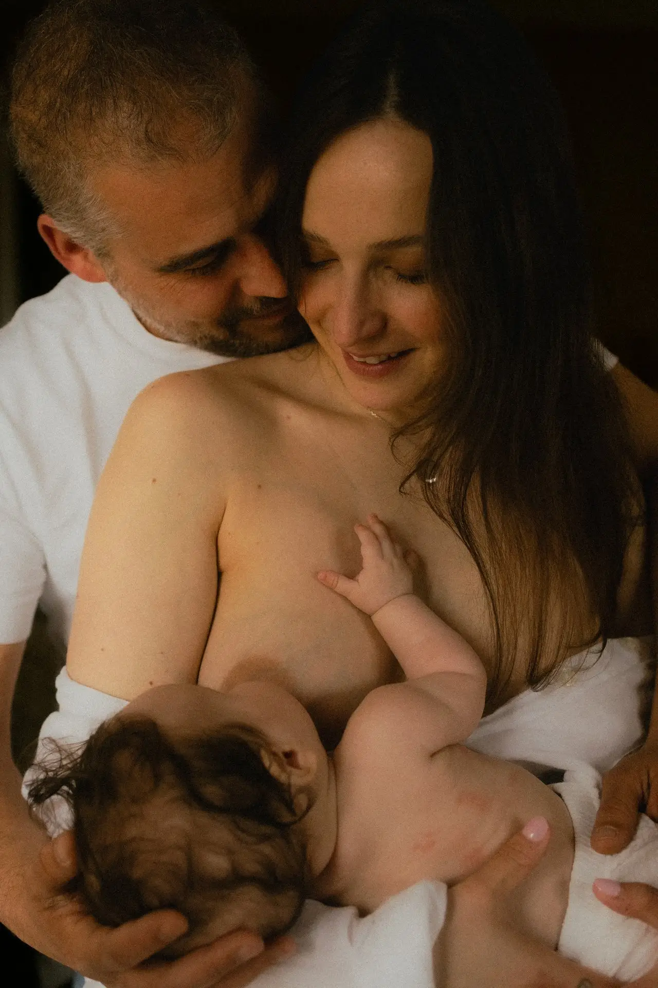 Parents tenant leur nouveau-né dans les bras lors d'une séance naissance en studio - Melissa Jai Photographe