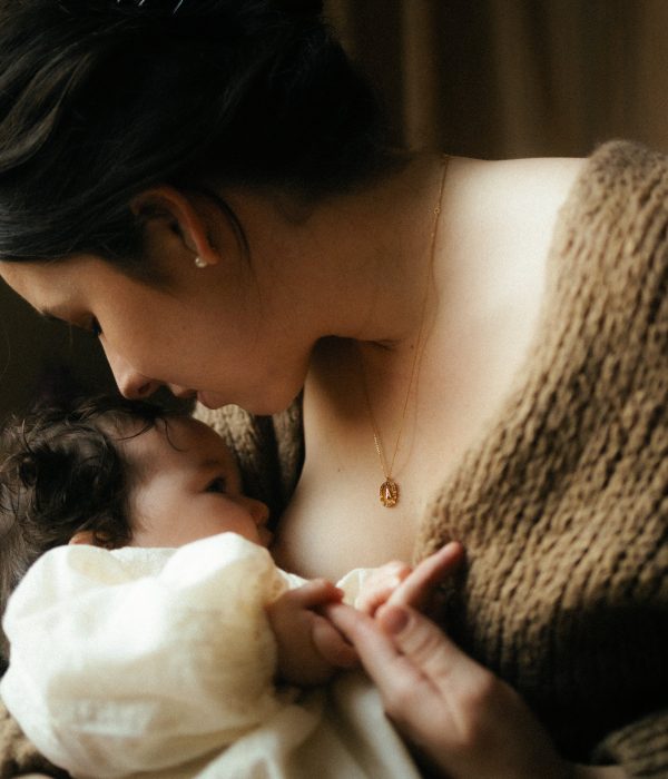 Gros plan allaitement maman allaitant bebe avec collier dore lumiere chaude photographe Melissa Jai