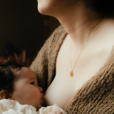 Maman allaitant son bebe avec un collier en or dans une lumiere douce et intimiste - Melissa Jai Photographe