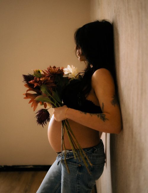 Femme enceinte tenant un bouquet de fleurs en lumiere doree lors d'une seance grossesse - Melissa Jai Photographe
