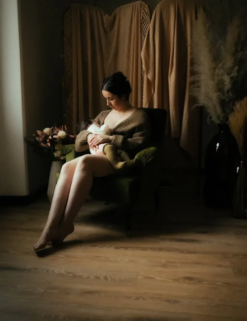 Femme enceinte assise sur un fauteuil en robe blanche lors d'une séance grossesse en studio - Melissa Jai Photographe
